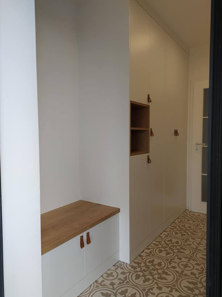 Sitzbank mit Holzplatte am Anfang der hellen Kastenwand