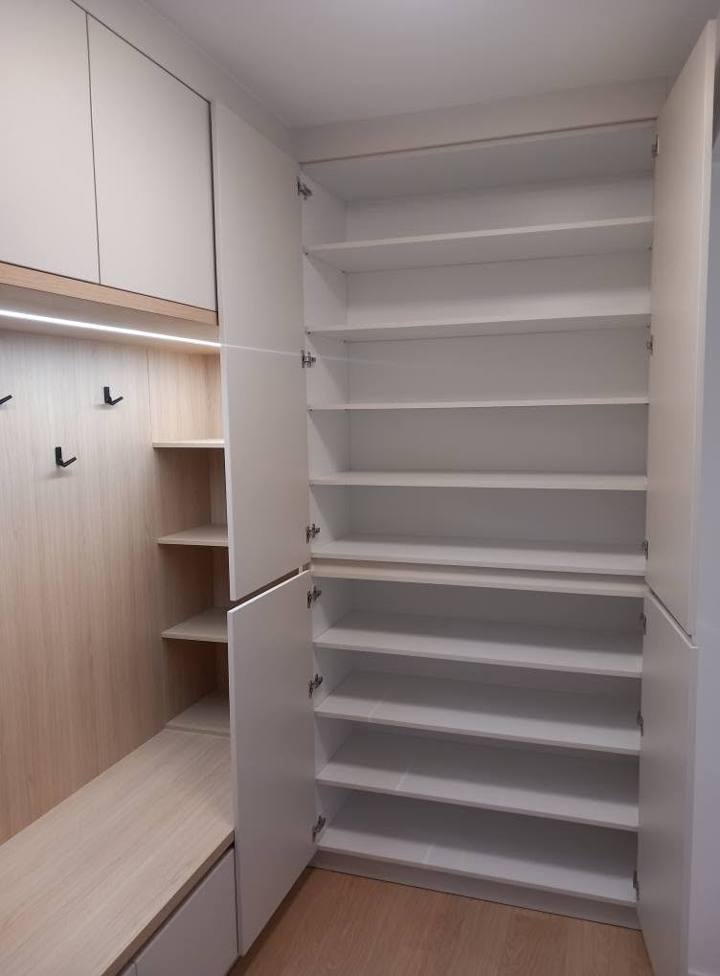 Vorzimmerkasten mit Tür und offenen weißen Schuhregalen.