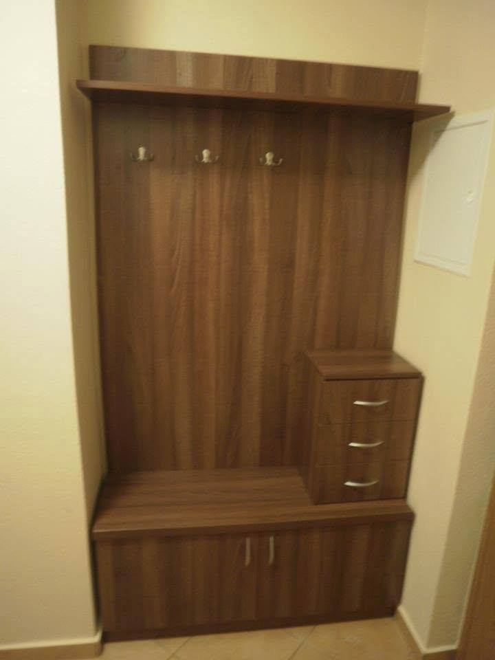 Garderobenwand in Nussbaumdekor mit Haken und niedriger Kommode im Vorzimmer.