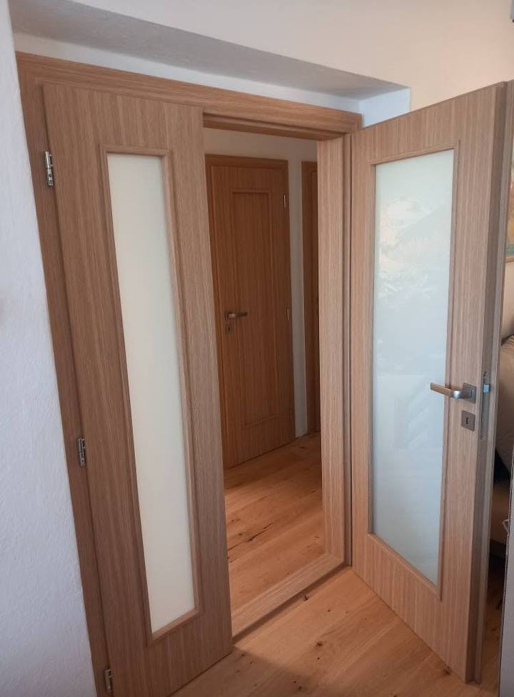 Verglaste Tür in heller Eiche zwischen gefliestem Vorzimmer und Zimmer