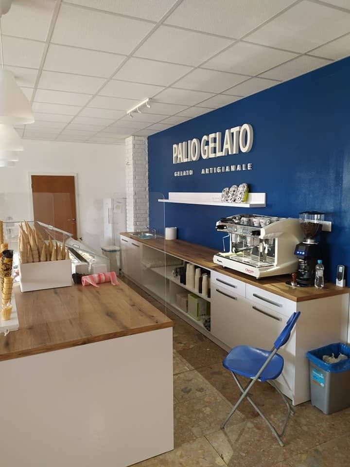 Innenraum der Gelateria mit weißer Theke, Eichenplatte und blauer Wand