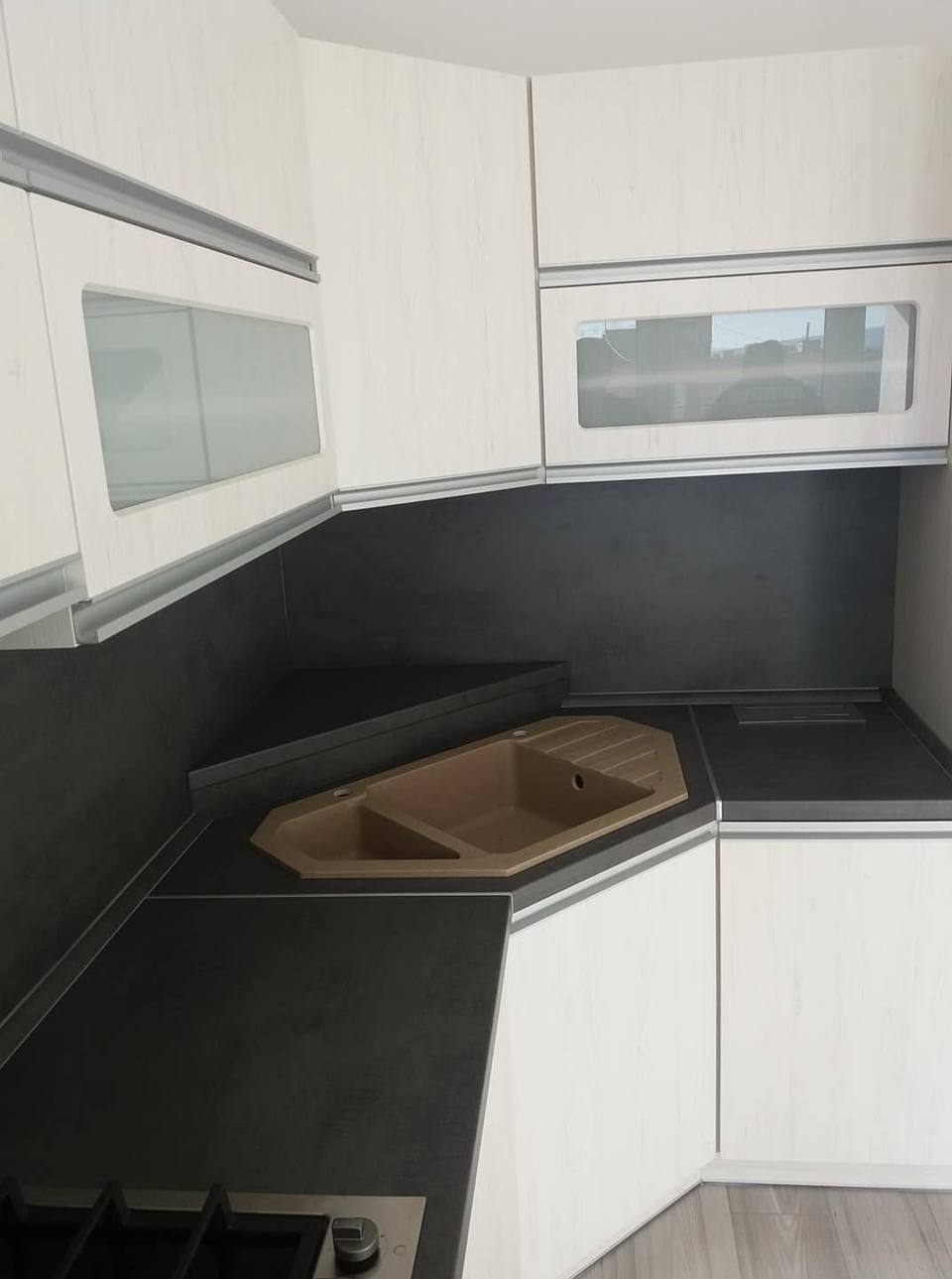 Küchenecke mit beiger Spüle und Oberkästen mit Satinatoglas