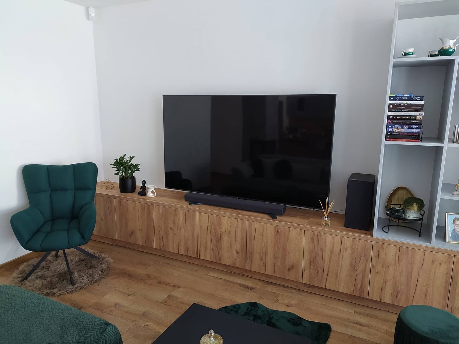 Langes Eichen-TV-Möbel mit Regal und grünem Sessel