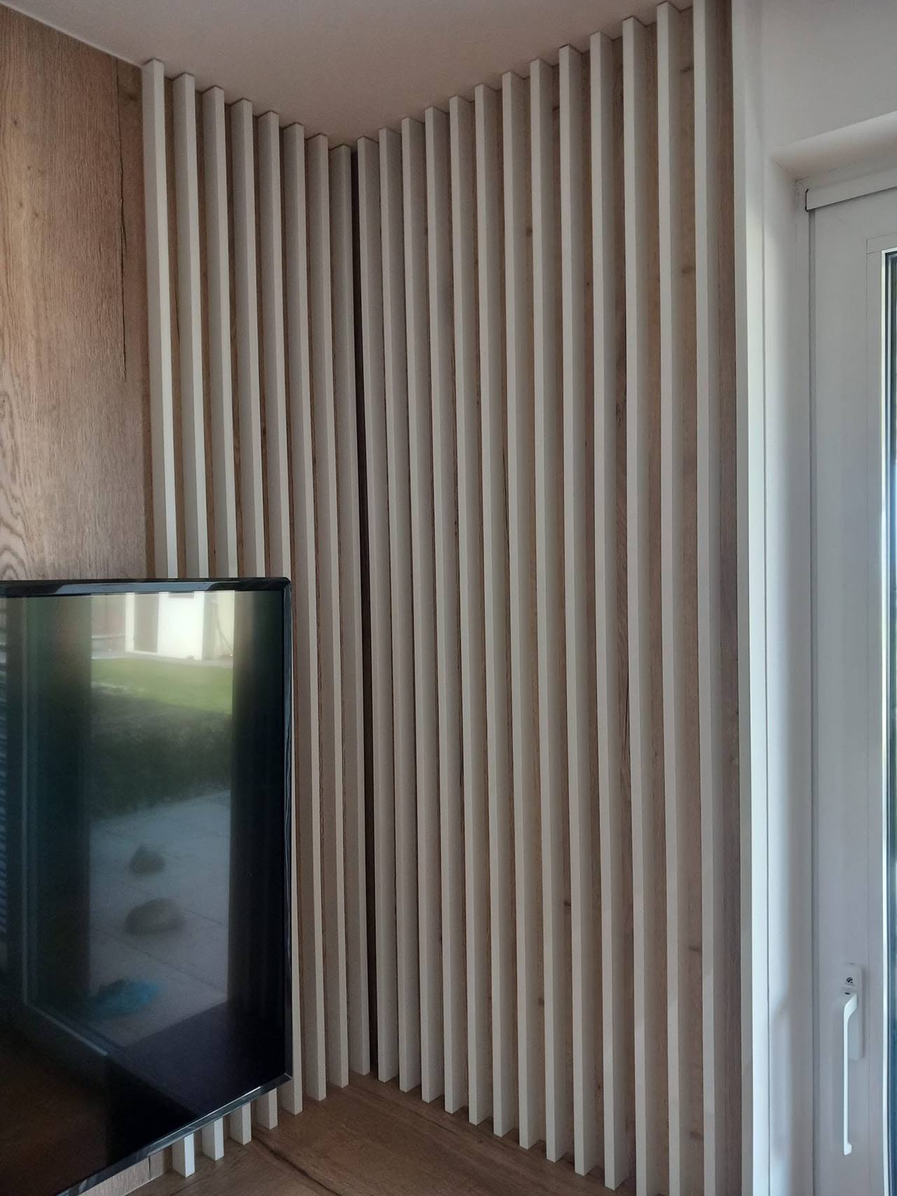Kút obložený svetlými zvislými lamelami vedľa televízora