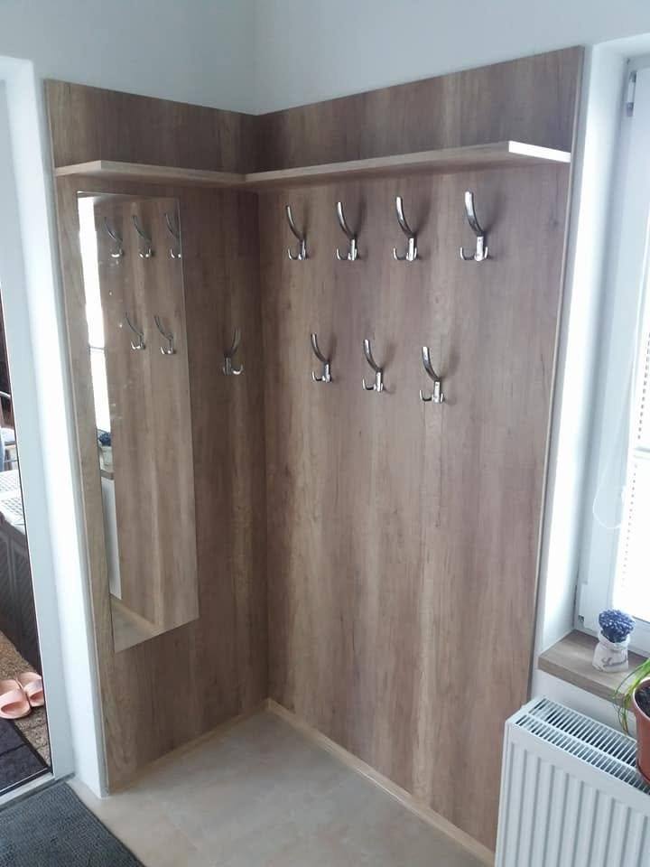 Eck-Garderobenwand in Eichendekor mit zwei Reihen Metallhaken.