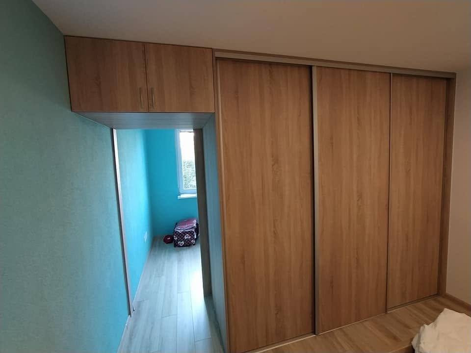 Eck-Einbaukasten mit Schiebetüren an der hellblauen Wand.
