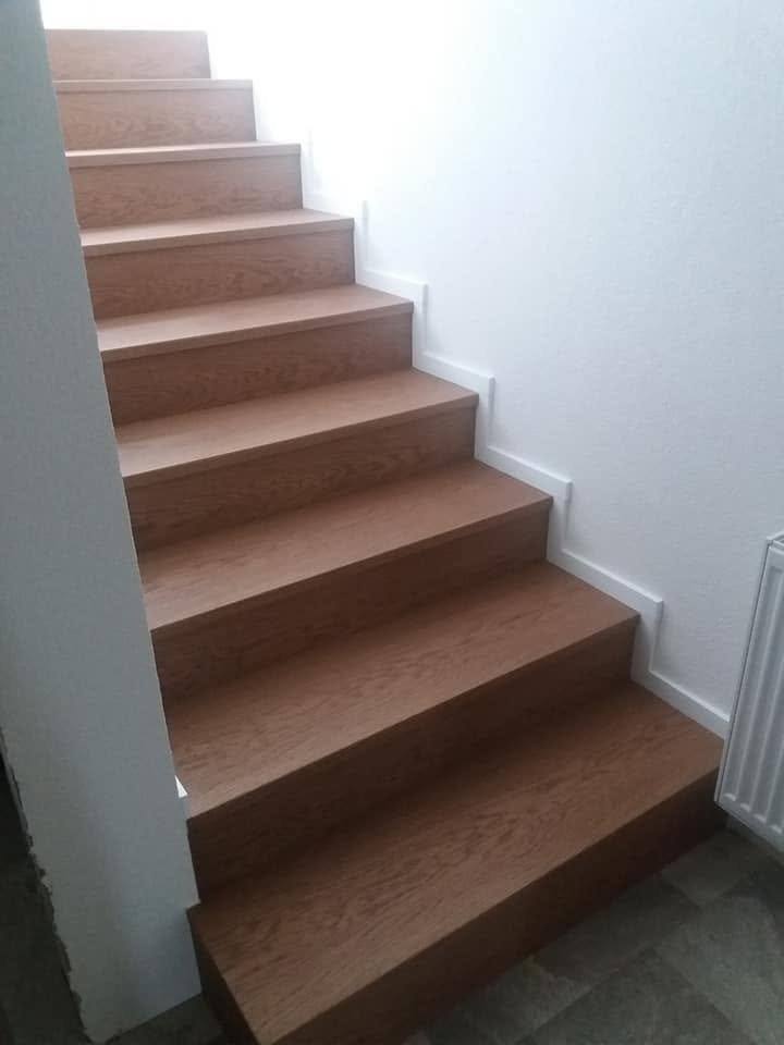 Gerade Eichenstiege in warmem Farbton an der weißen Wand mit Heizkörper