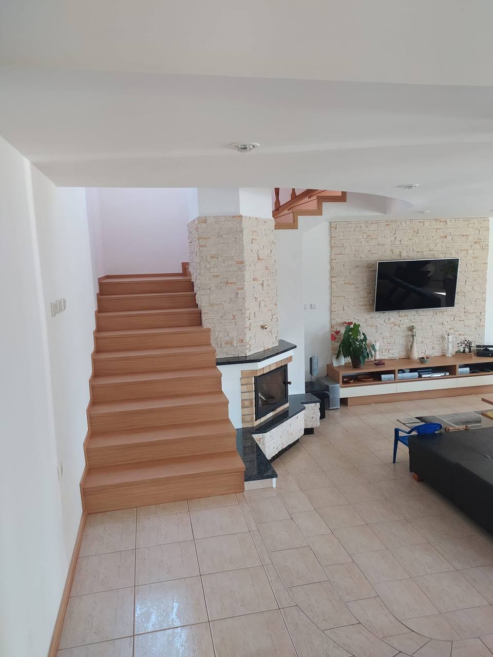 Gerade Eichenstiege im Wohnzimmer neben Kamin und Fernseher