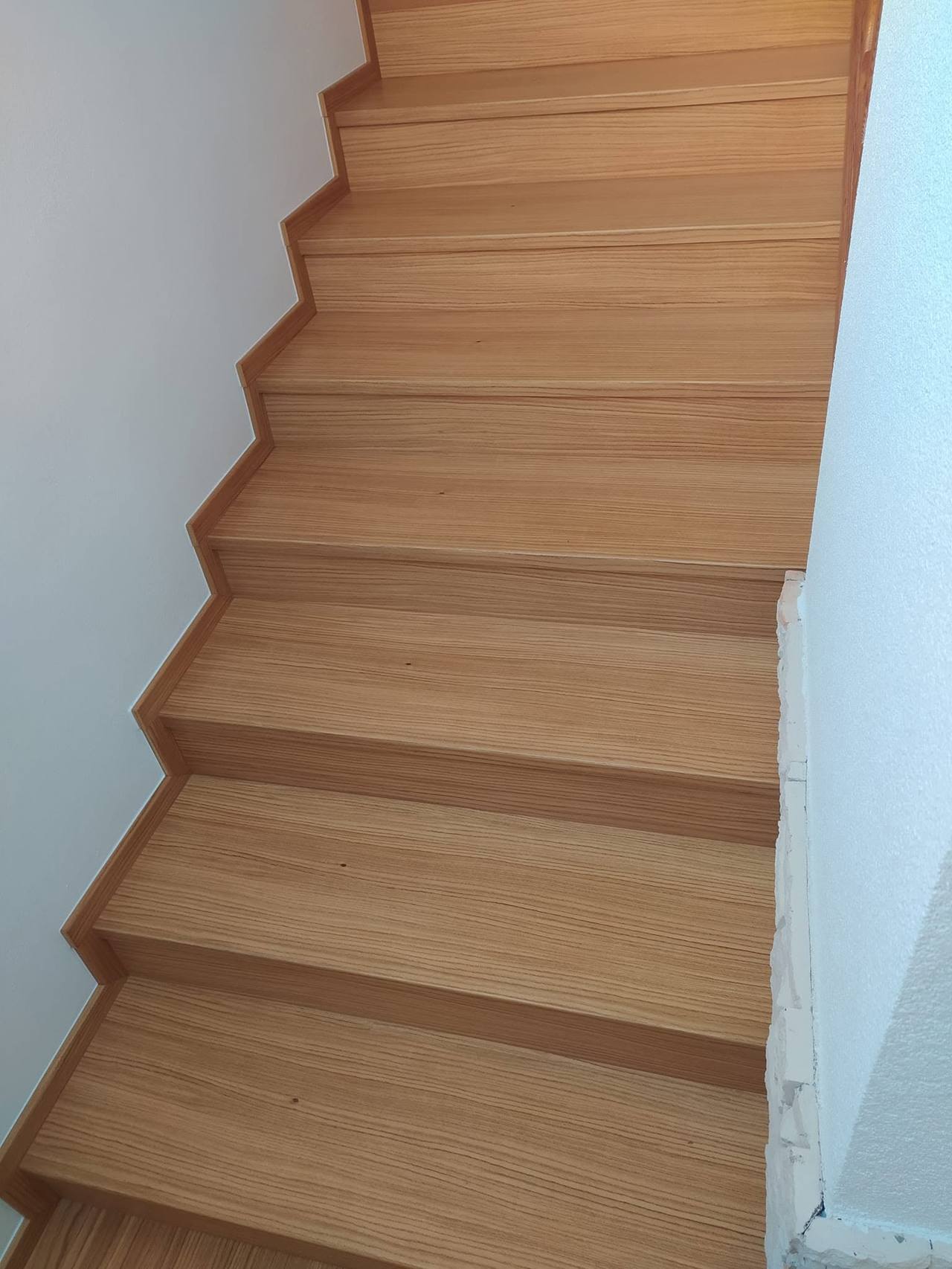 Gerade Eichenstiege entlang weißer Wände aus anderem Winkel