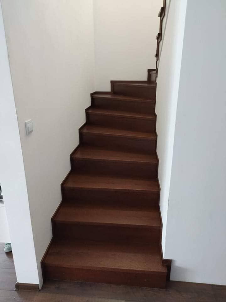 Gerade Stiege mit dunkler Eichenverkleidung zwischen weißen Wänden