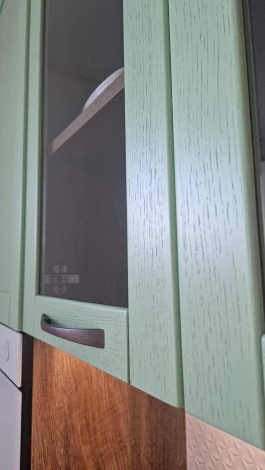 Grüner Rahmenkasten mit Glastür über der Eichen-Rückwand