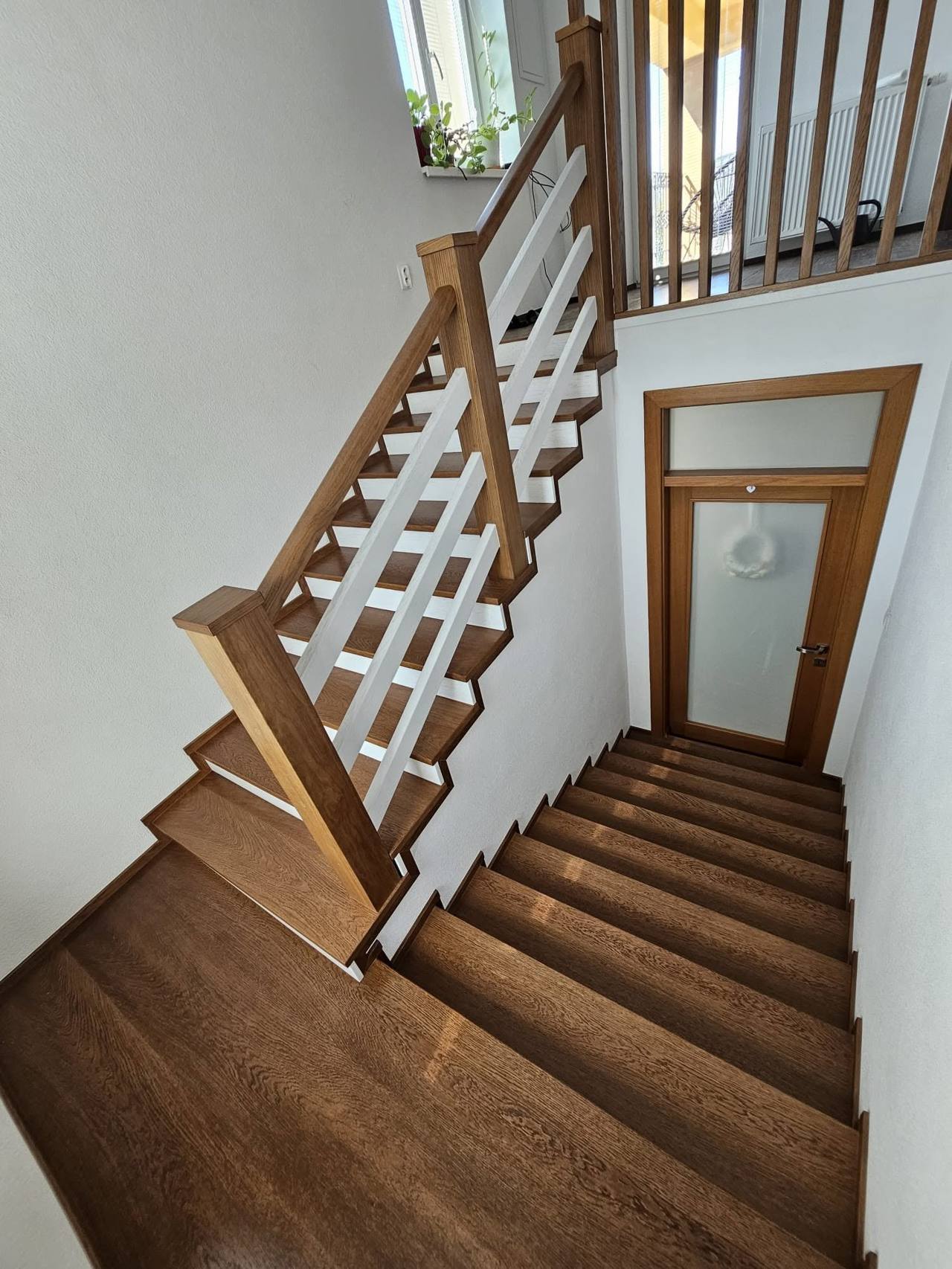 Eichenstiege mit weißer Kreuzgitterfüllung und Galerie im Hintergrund