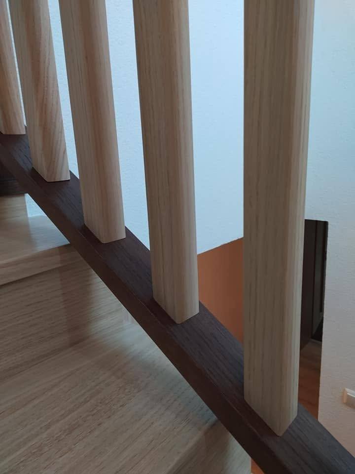 Blick von unten auf die Stiege mit weißen Stäben und dunklem Handlauf