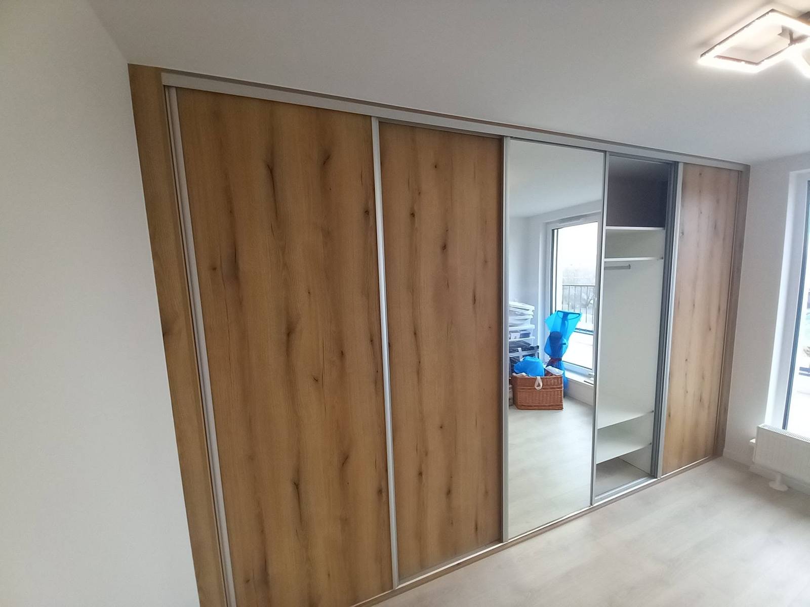 Schiebetürenkasten in Eichendekor mit Spiegeltür im hellen Zimmer