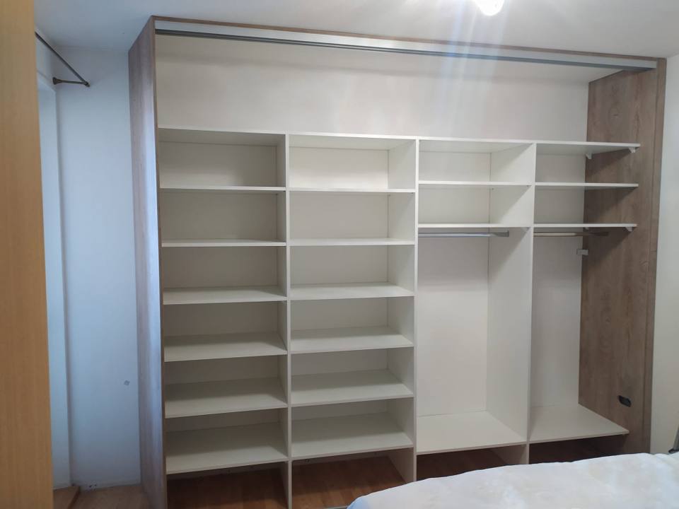 Breiter weißer Innenausbau des Einbaukastens mit Fachböden und Kleiderstangen.