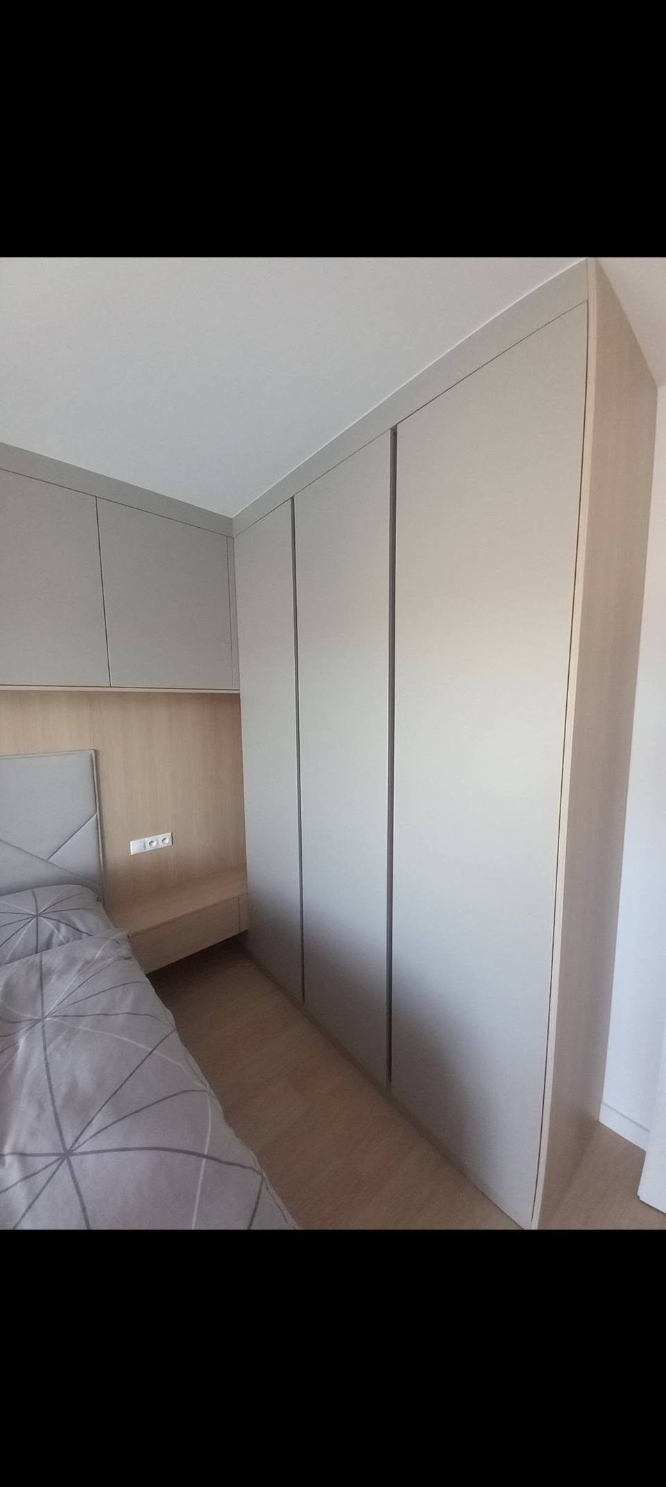 Grauer griffloser Kasten neben dem Bett im Schlafzimmer