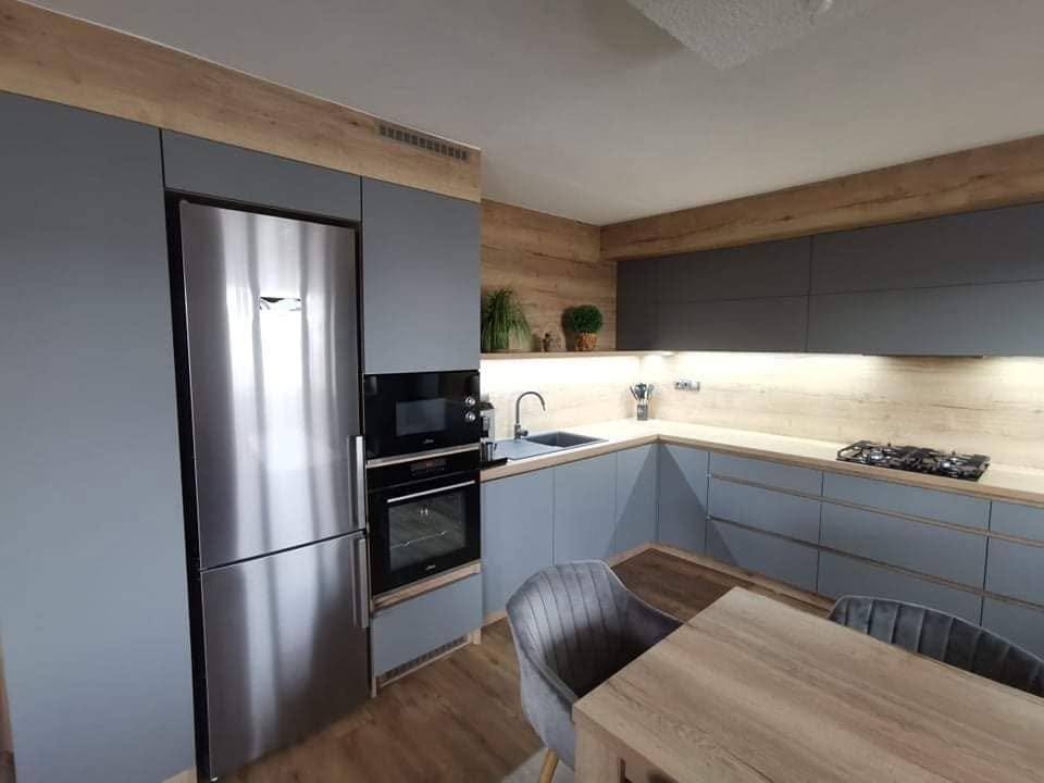 Blick auf Kühlschrank und graue Zeile mit Eichenblende oben