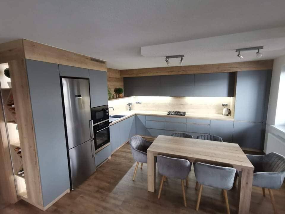 Offene graue Küche mit beleuchteter Rückwand und Esstisch mit Stühlen