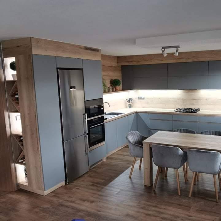 Edelstahl-Kühlschrank und Backrohr in grauen Hochkästen mit Eichenrahmen