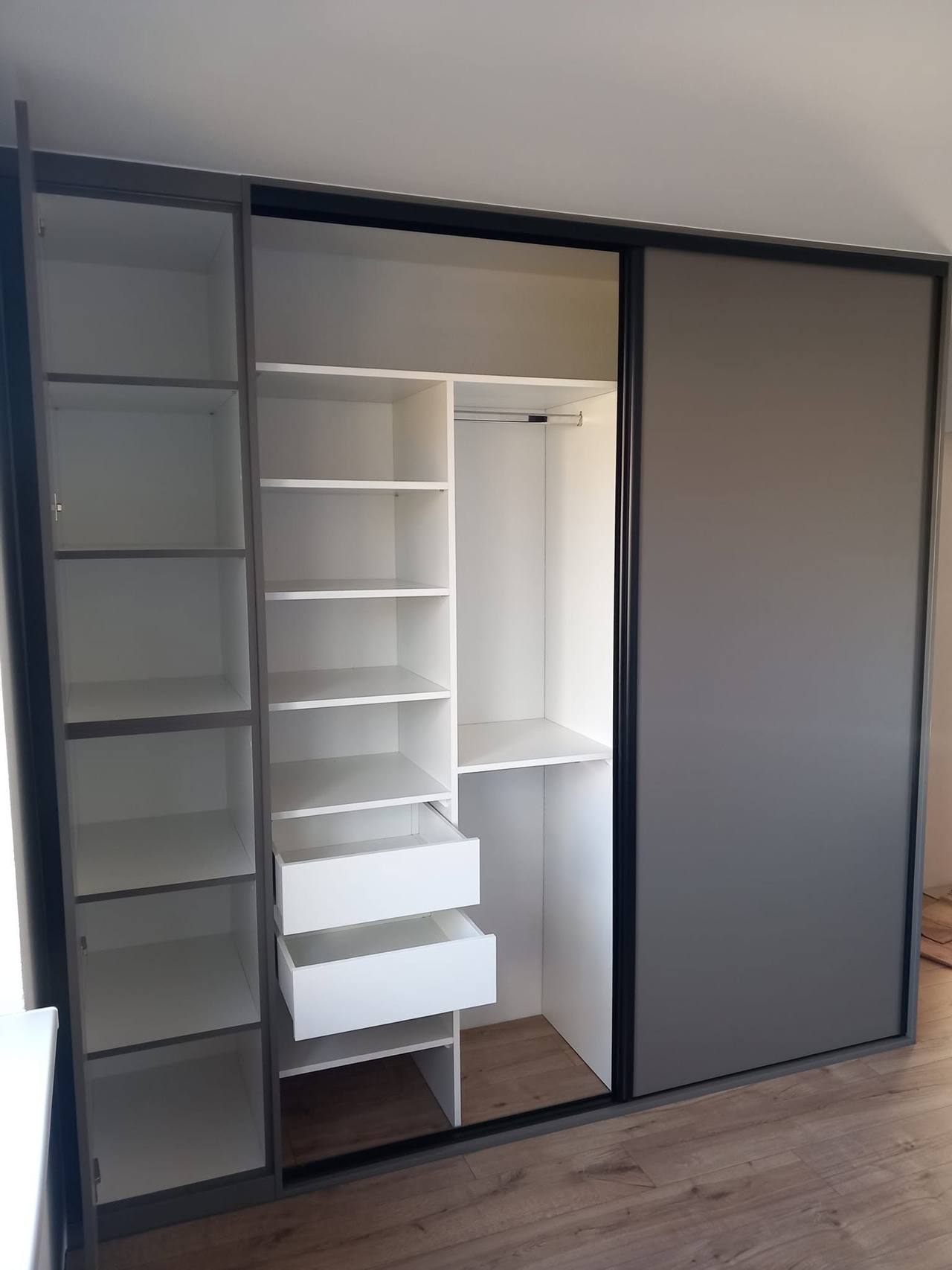 Offener grauer Kasten mit weißen Fachböden und herausgezogenen Laden