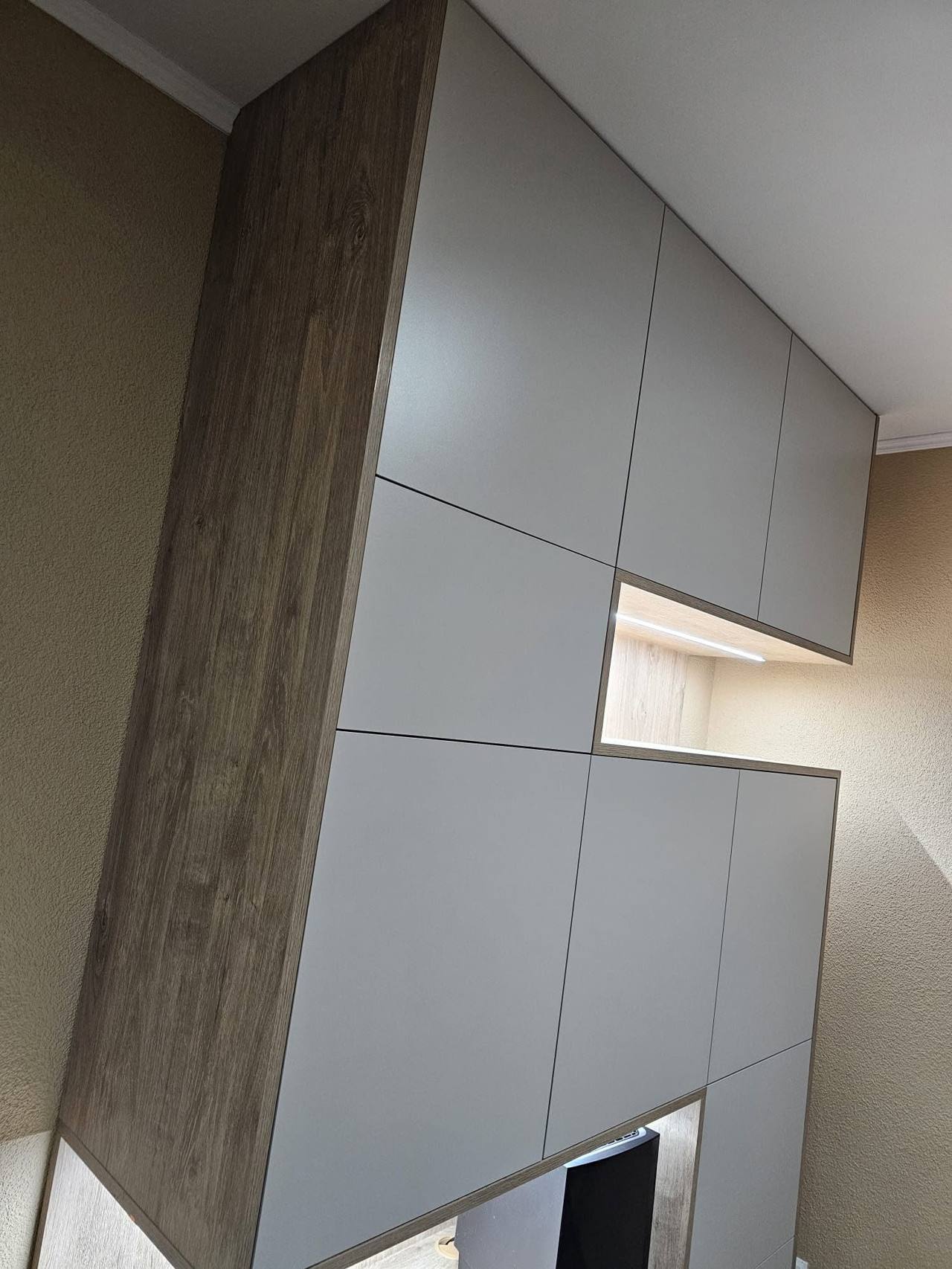 Graue Schrankwand mit Eichen-Seitenteil und beleuchteter Nische