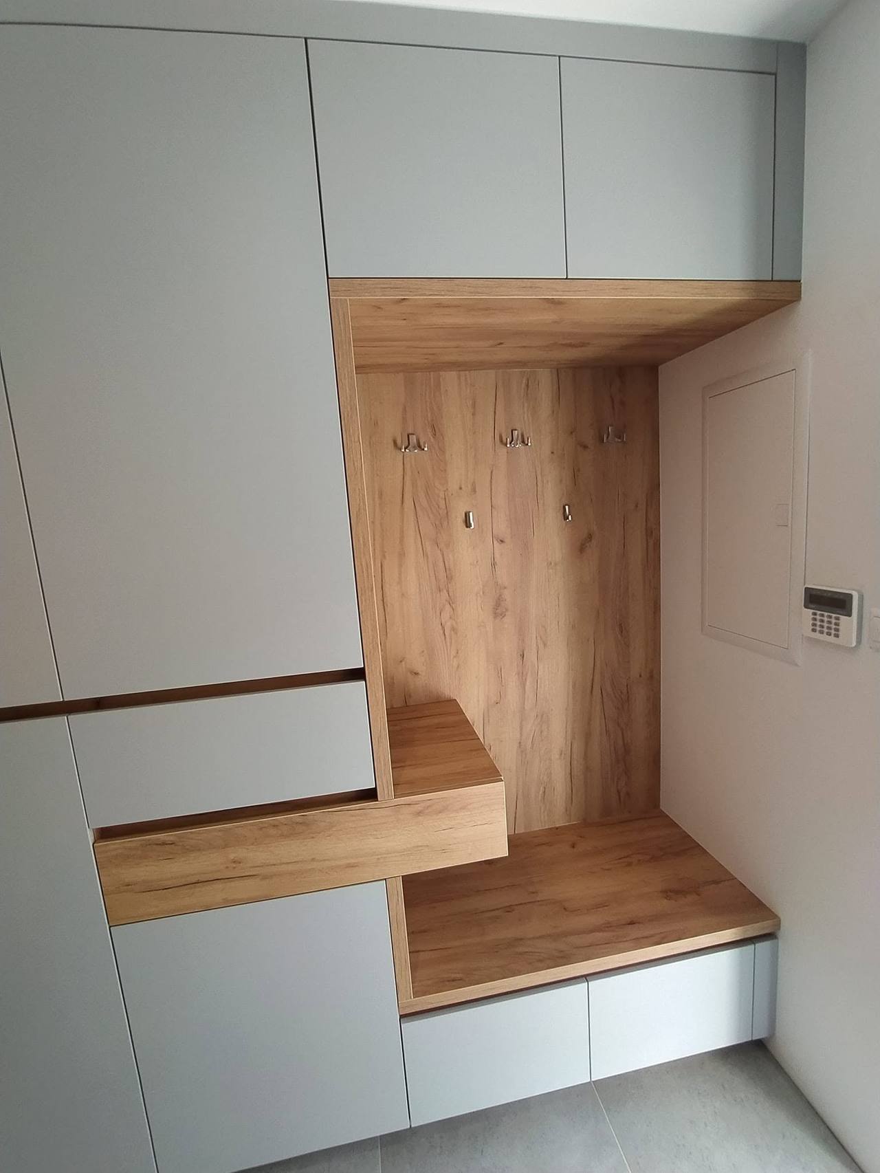 Graue Kastenwand mit Eichennische und auskragender Ablage