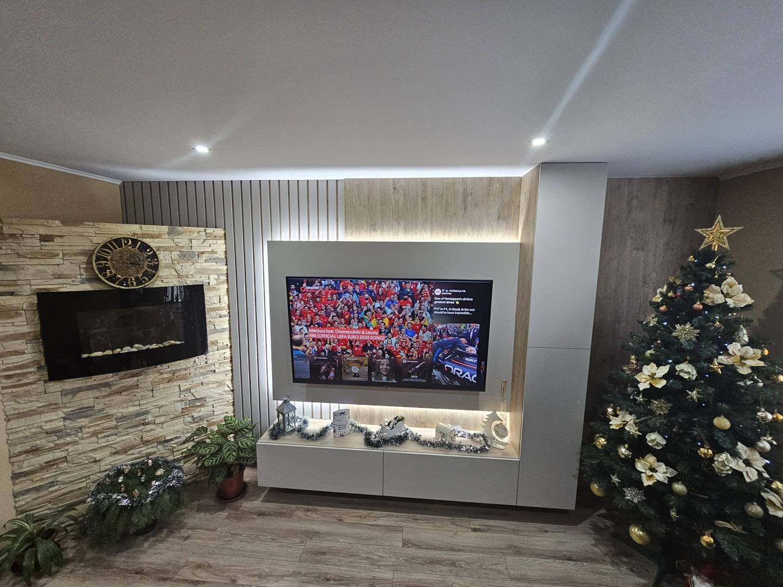 Sivá TV stena s podsvietením vedľa kamennej steny s krbom