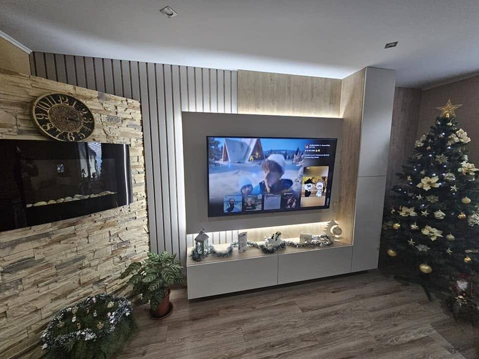 Podsvietená TV stena so sivými skrinkami pri krbe