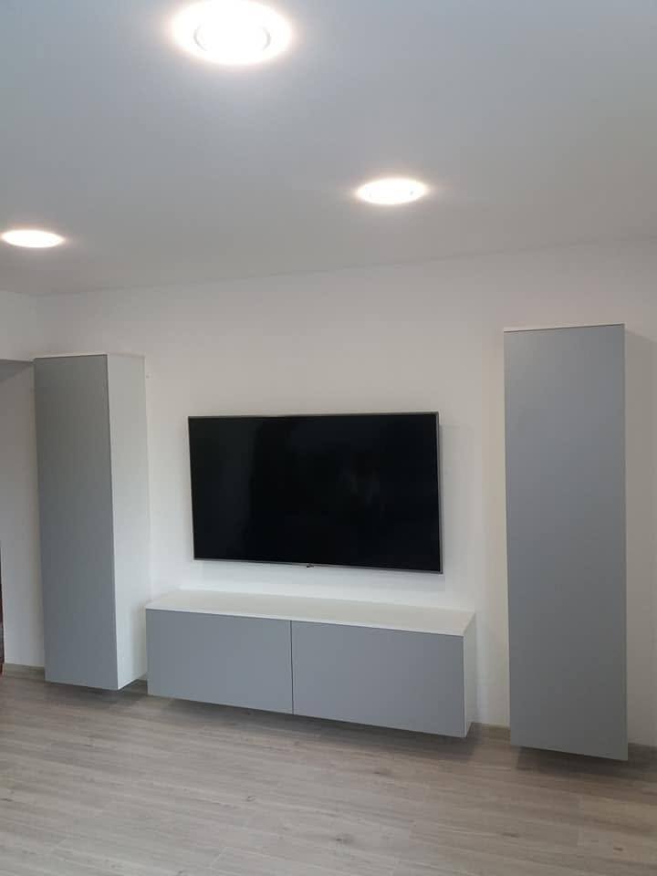 Minimalistische TV-Wand mit grauen Hochkästen und niedrigem Lowboard