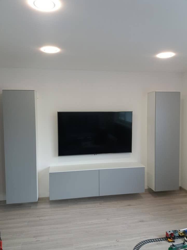 TV-Wand mit grauen Kästen und hängendem Lowboard unter dem Fernseher