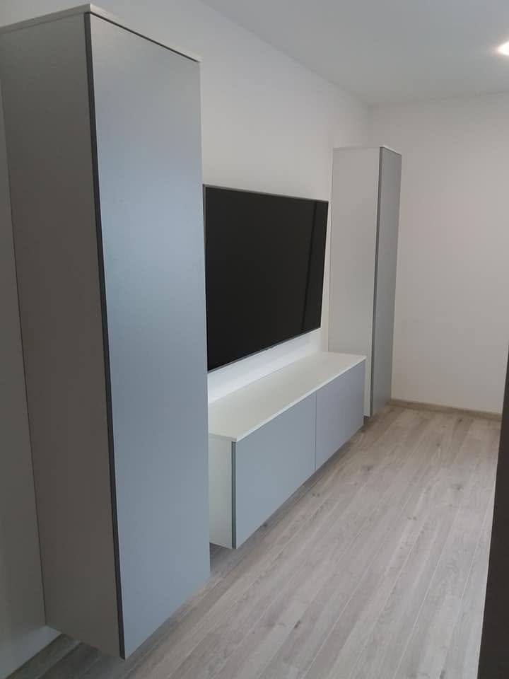 Grauer Hochkasten und hängendes Lowboard im weißen Wohnzimmer