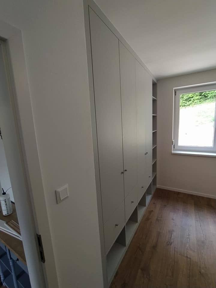Blick entlang des grauen Einbaukastens mit Fächern am Fenster