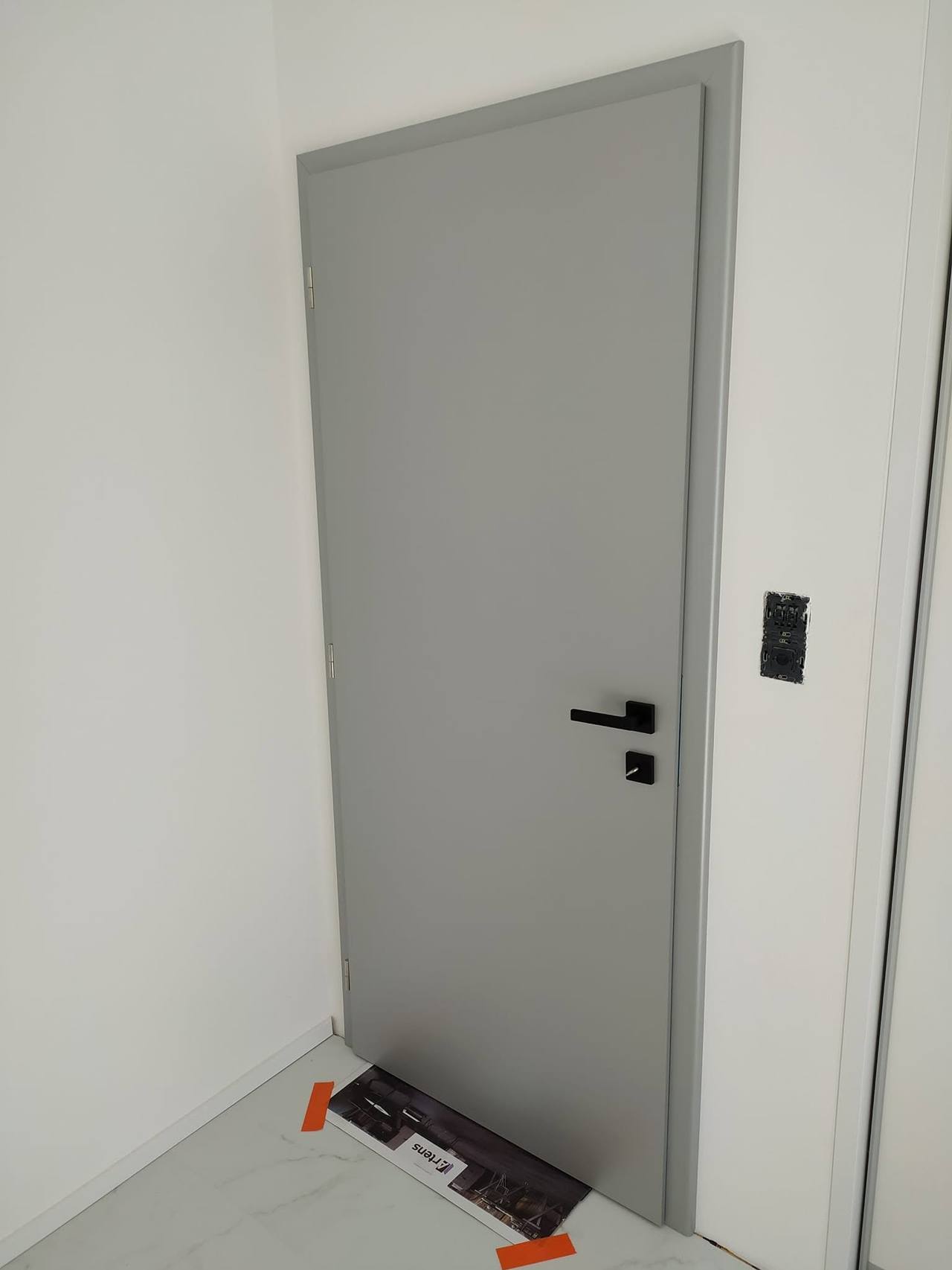 Graue Volltür mit schwarzer Klinke gleich nach der Montage