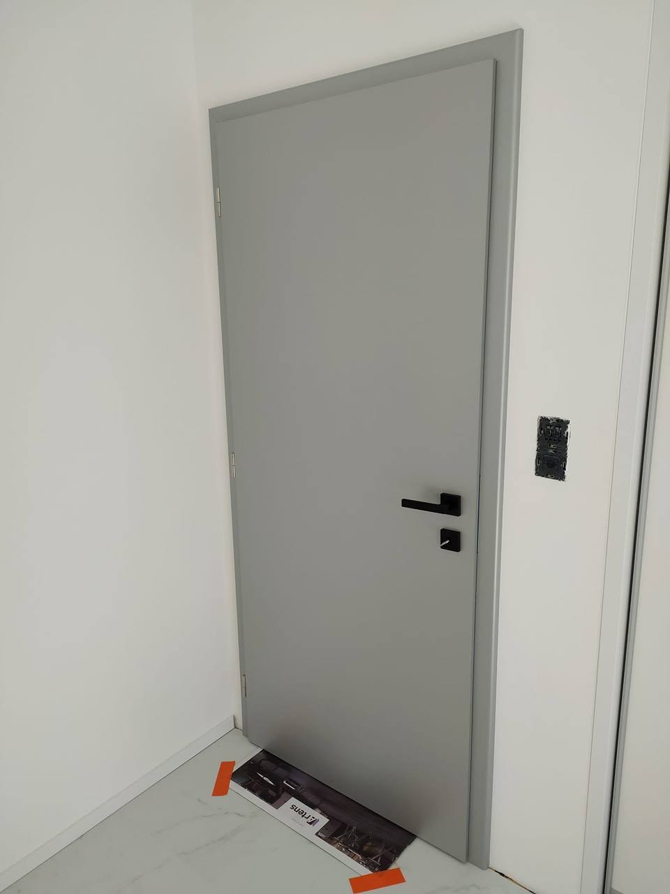 Graue Volltür mit schwarzer Klinke gleich nach der Montage