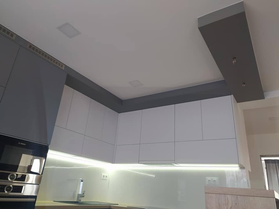 Weiße Oberkästen mit LED-Band über der Glasrückwand