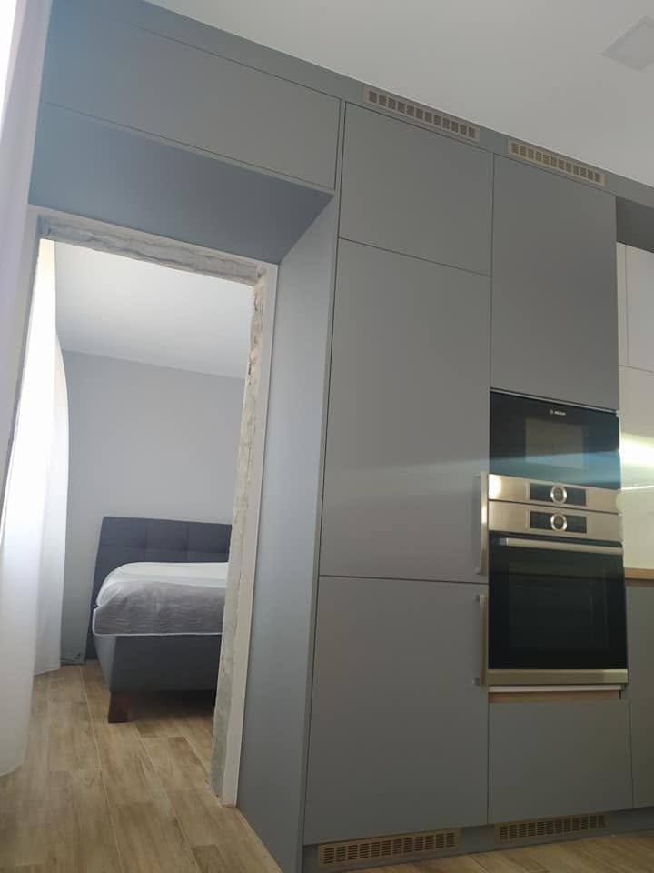 Graue Hochkästen mit Einbau-Backrohr beim Durchgang ins Zimmer