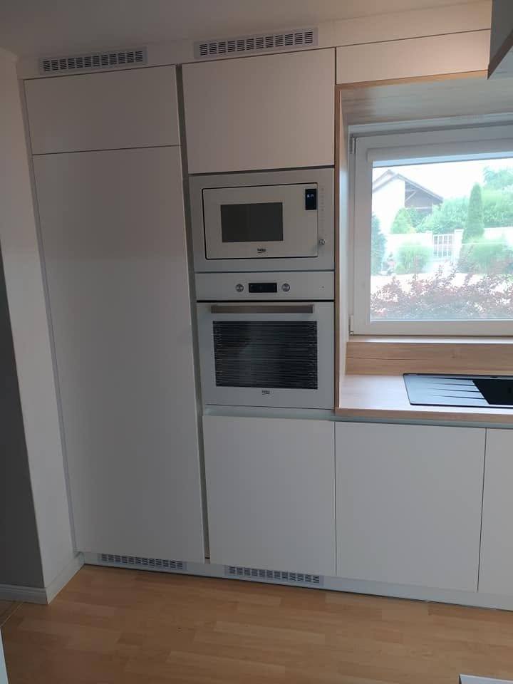 Graubeige Hochschrank-Zeile mit Einbaubackrohr und Mikrowelle am Fenster