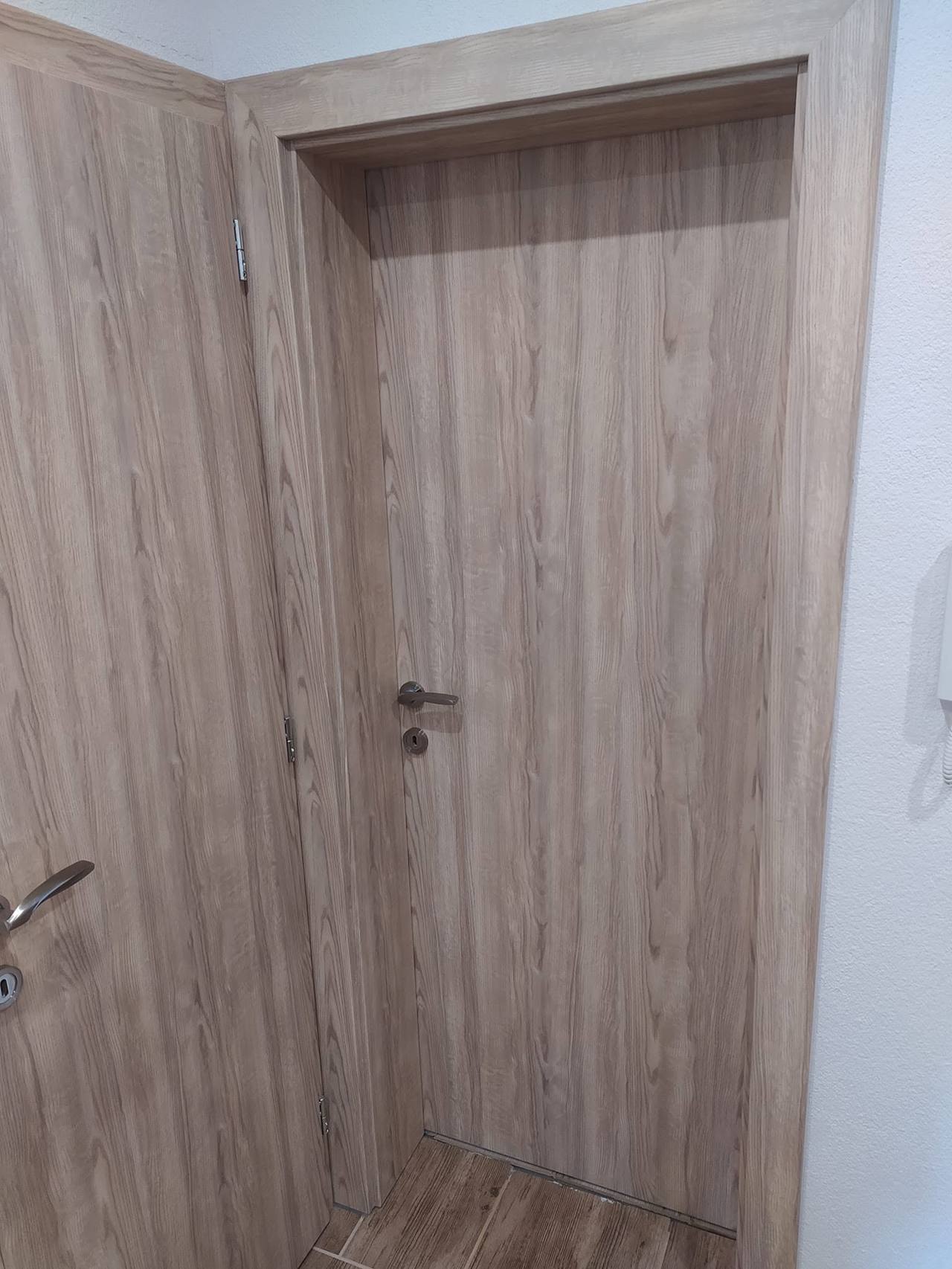 Sivohnedé dvere spredu s tmavou kľučkou