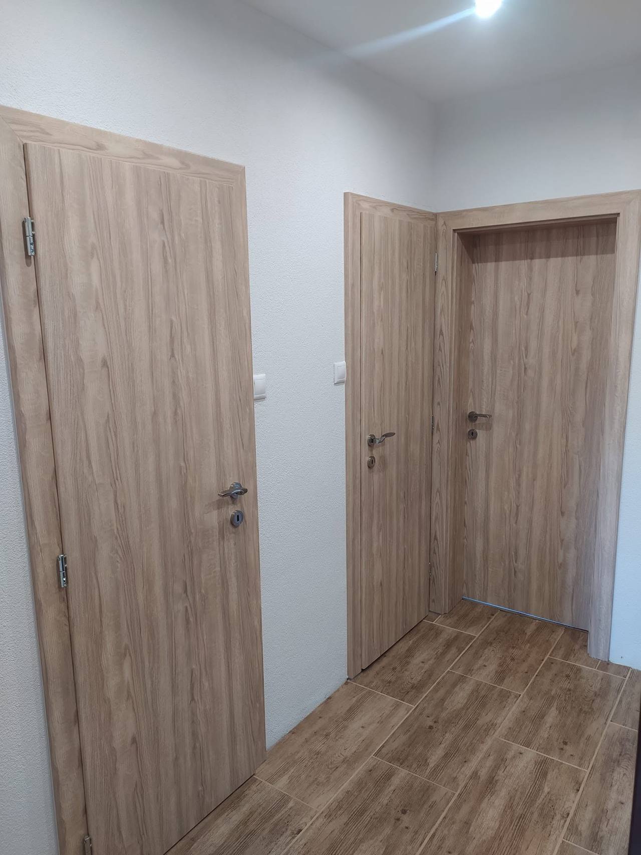 Dvoje zhodných sivohnedých dverí vedľa seba v chodbe