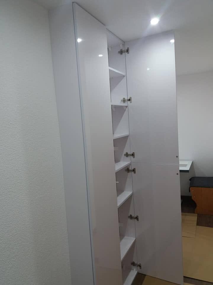 Weißer Hochkasten mit leicht geöffneter Tür und Regalen