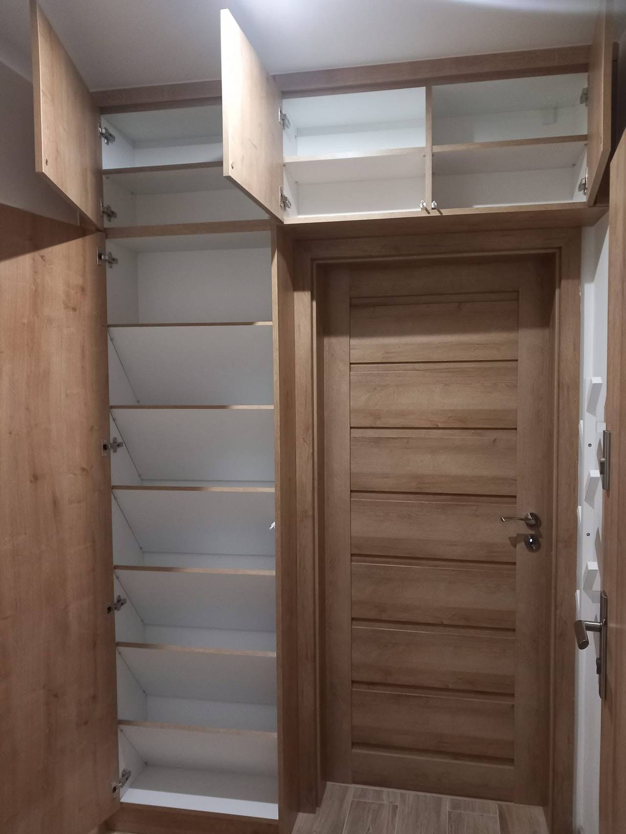 Geöffneter Kasten rund um die Tür mit Schuhböden und Aufsatz