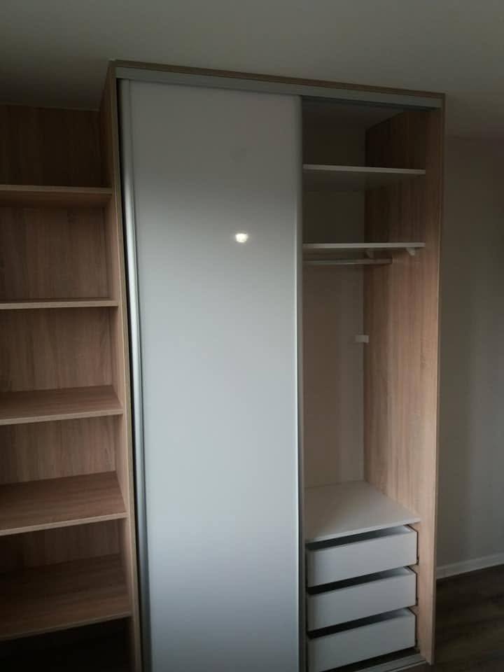 Odsunuté dvere odhaľujú tyč na vešanie a tri biele zásuvky