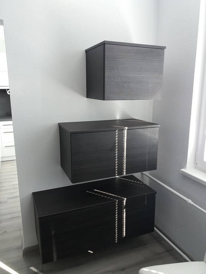 Drei hängende dunkle Schränkchen mit Metallstreifen an der Wand