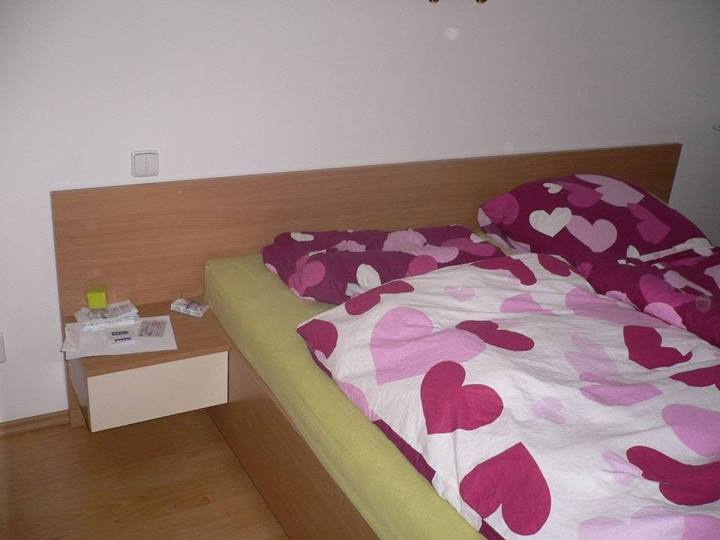Doppelbett mit Eichen-Kopfteil und weißem Nachtkästchen