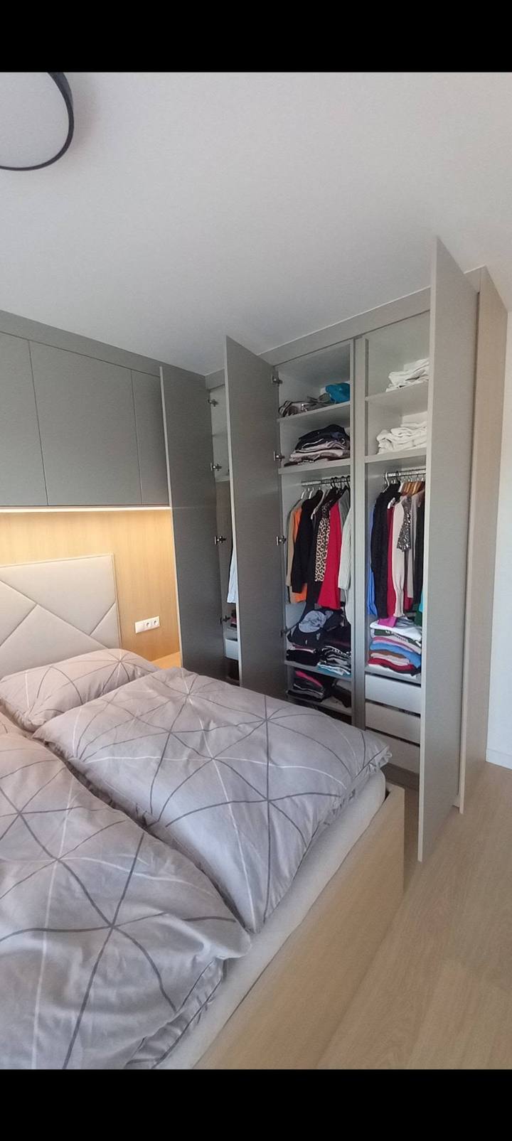 Schlafzimmer mit Bett und offenem grauem Einbaukasten