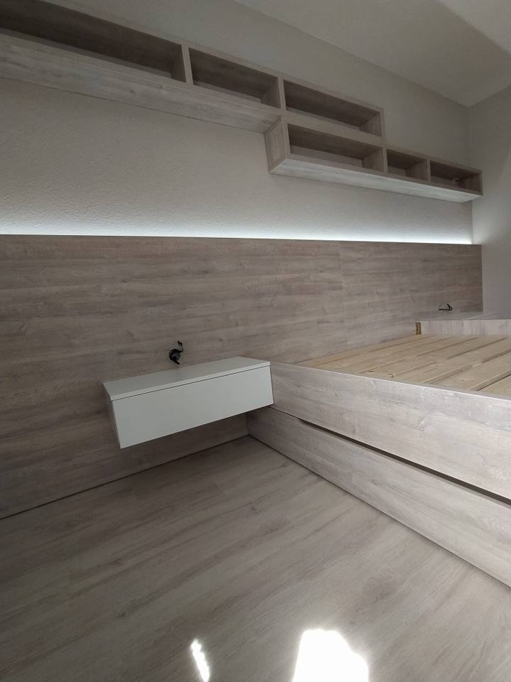 Zimmer mit Eichenwandverkleidung, Bett und beleuchteten Regalen