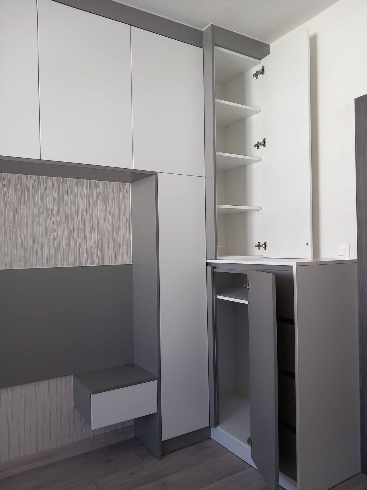 Weißer Kasten mit offenen Fächern, grauer Verkleidung und Nachtkästchen