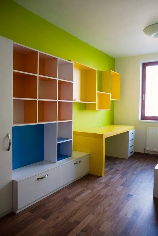 Študentská izba s farebnou knižnicou a stolom pri stene