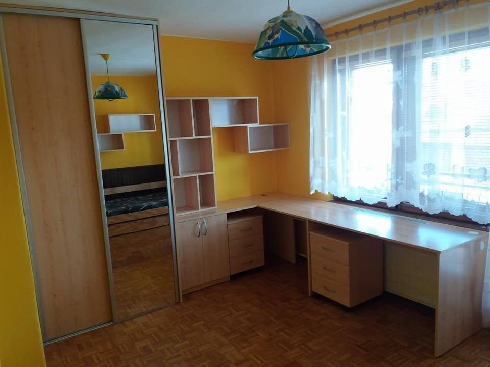 Zimmer mit Spiegel-Schiebetürkasten und langem Tisch unter dem Fenster
