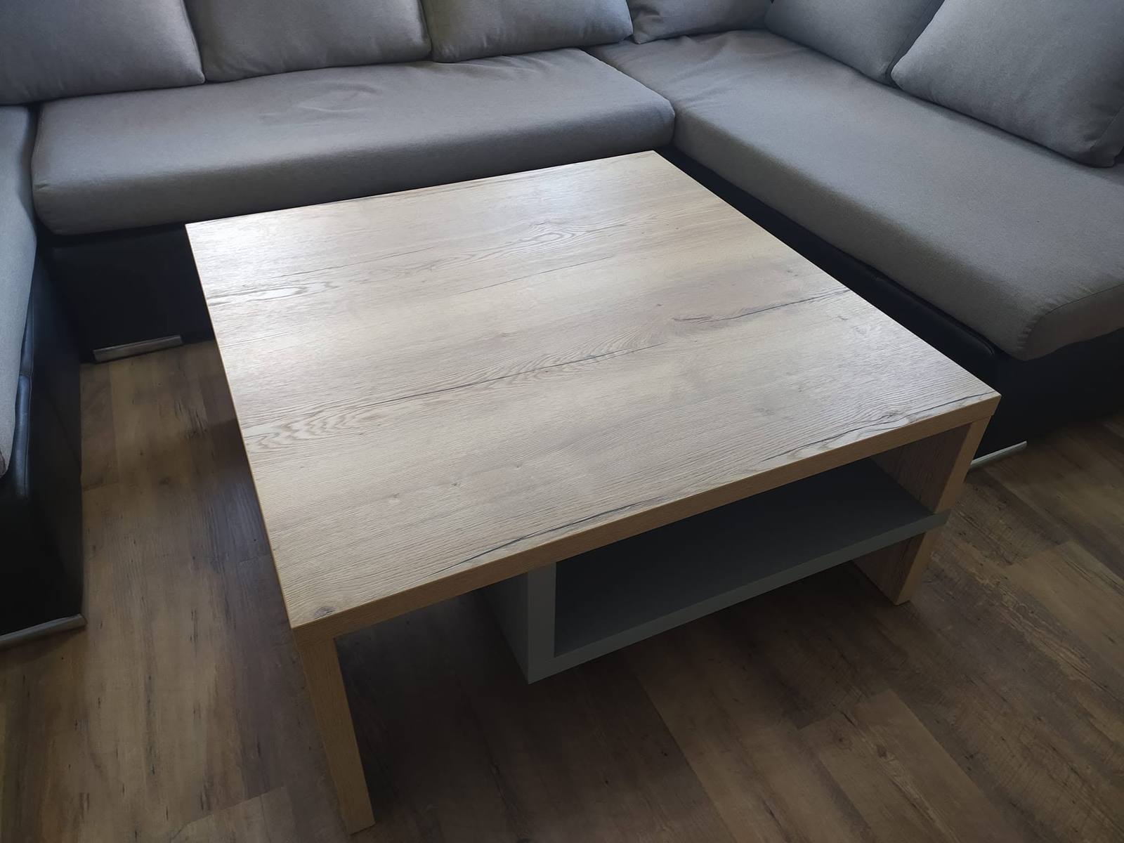 Quadratischer Couchtisch in Eichenoptik neben dem grauen Sofa